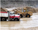 Dump truck and bulldozer in dirt mine with standing water
