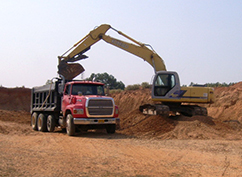 Track hoe loads a dump truck at a sand and gravel mining operation